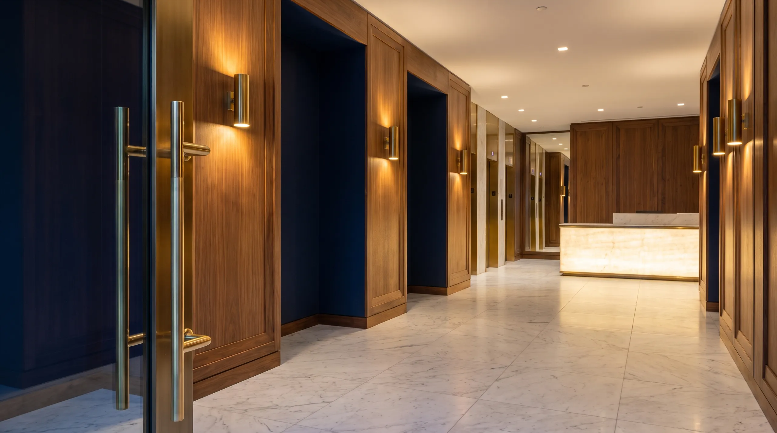 Recepción de un edificio residencial con paneles de madera, mármol y apliques de bronce