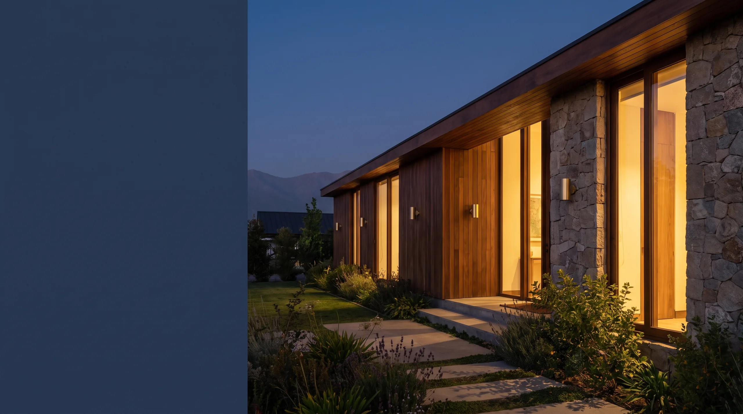 Fachada de una casa moderna de madera y piedra iluminada al anochecer